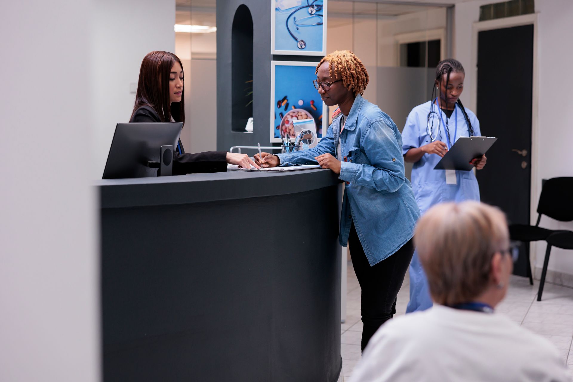 A woman is standing at a counter in a hospital talking to a doctor.